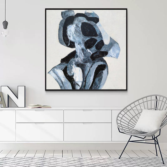 Abstract art piece in a modern living room setting with a chair and white wall.