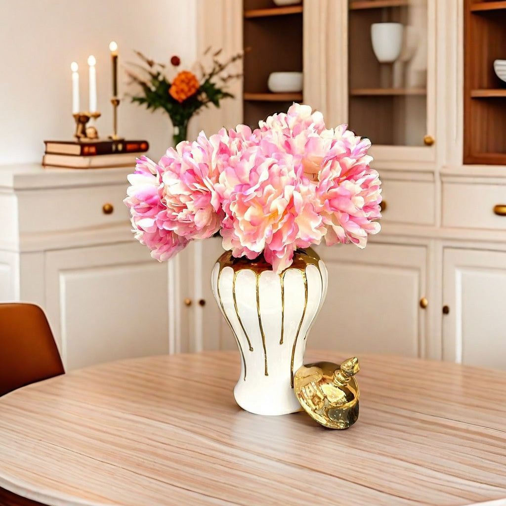 Pink flowers in a white vase on a wooden table with a blurred background