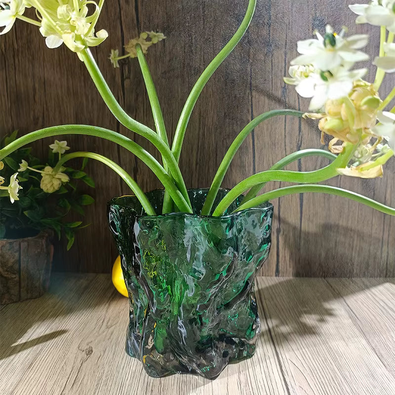 Green textured vase with flowers on a wooden surface