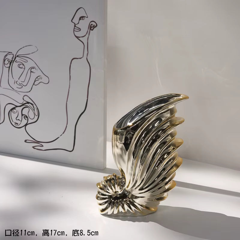 Decorative sculpture resembling a shell on a white surface with abstract art in the background.