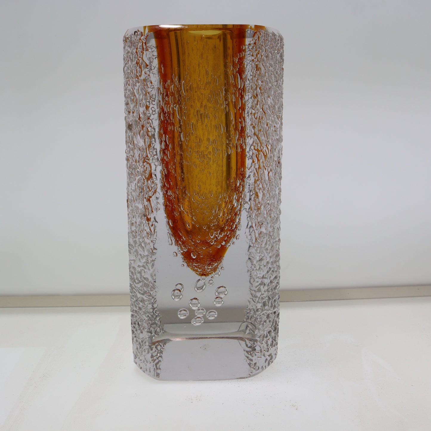Tall glass vase with textured design on a white background