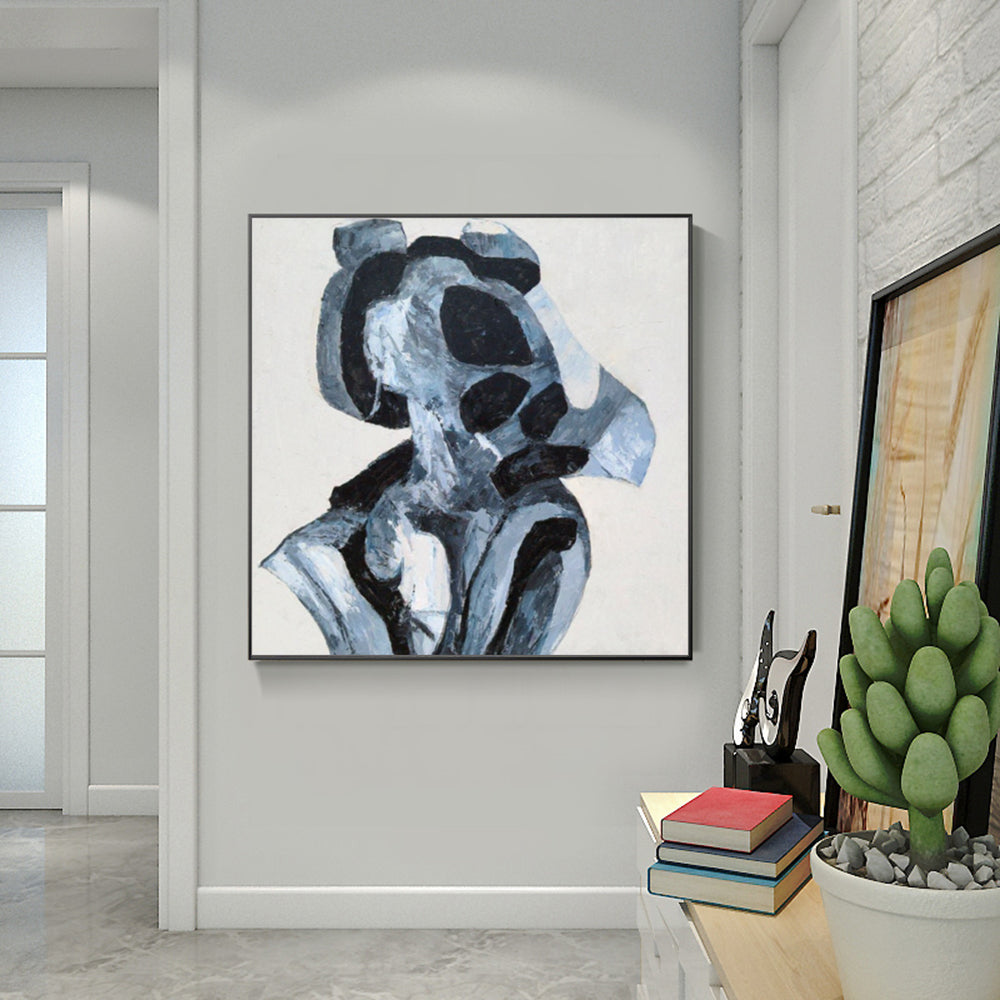 Abstract art piece on a wall in a modern interior setting with books and a plant.