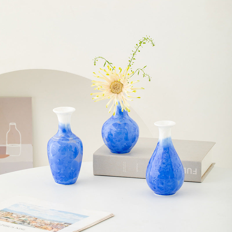 Three blue vases on a white surface with a white background