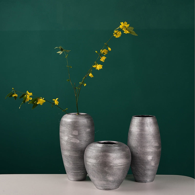 Three gray ceramic vases with yellow flowers against a green background