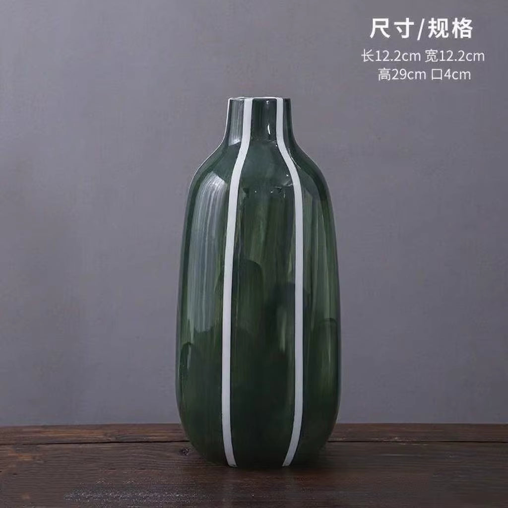 Green vase with white stripes on a wooden surface and gray background