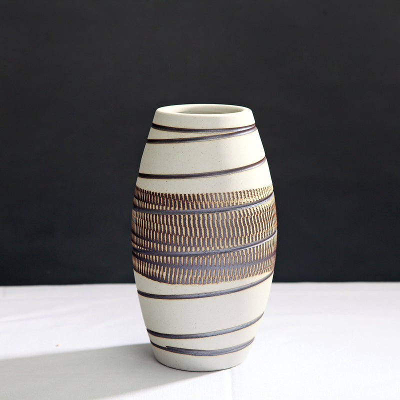 Ceramic vase with striped design on a white surface and black background