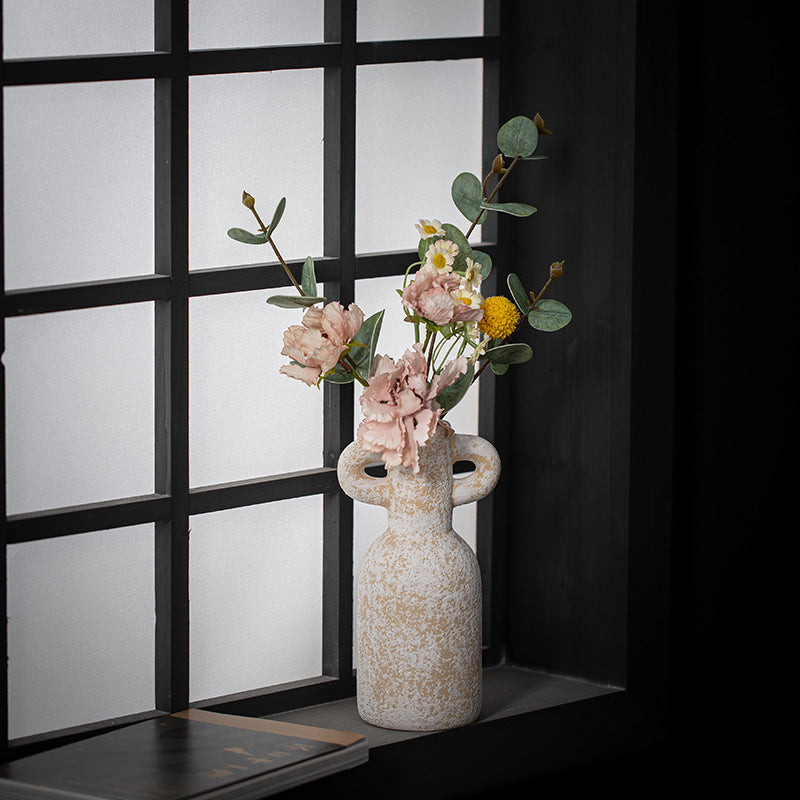Decorative vase with flowers against a window pane background