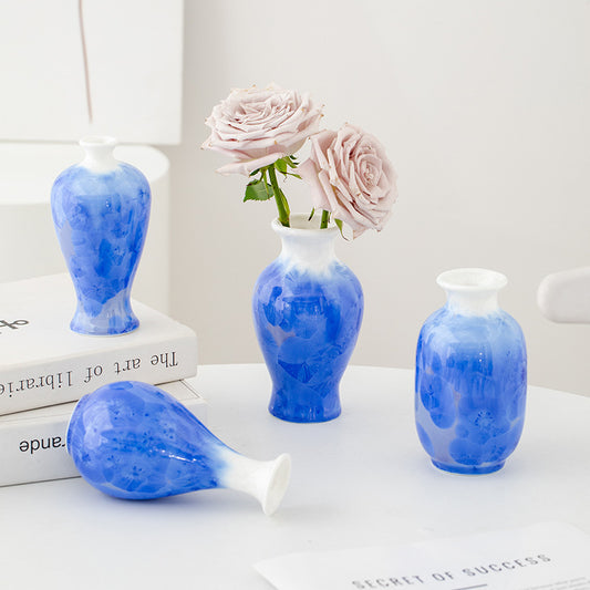 Set of blue ceramic vases with a white base on a light surface.
