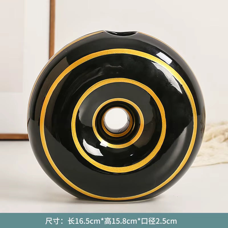 Black ceramic vase with gold concentric circles on a white background