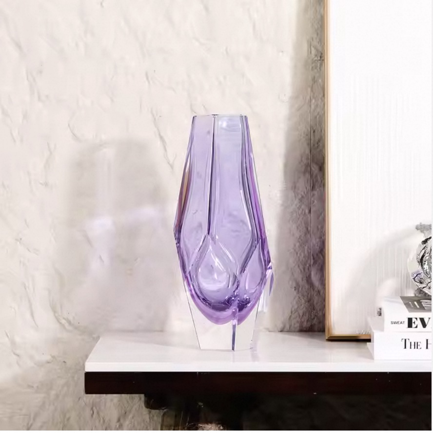 Purple glass vase on a white surface with a neutral background