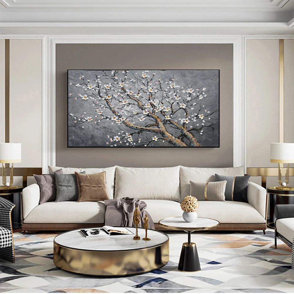 Modern living room with a large painting of floral branches on the wall above a beige sofa.