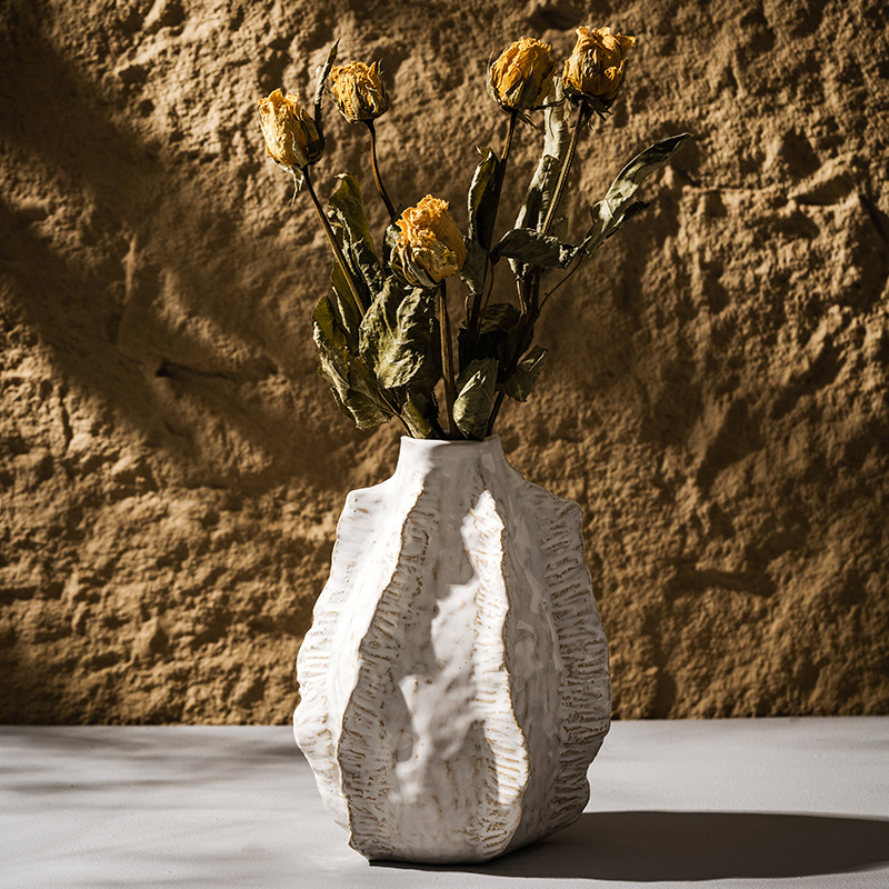 White textured vase with dried flowers against a textured brown wall