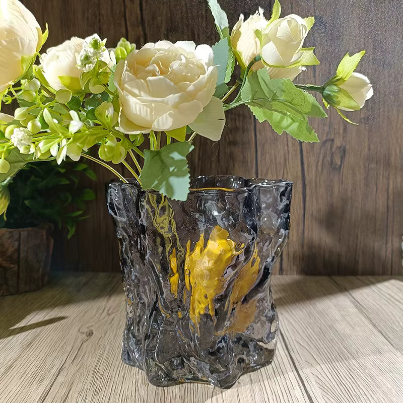 Decorative vase with a textured design holding white flowers on a wooden surface.