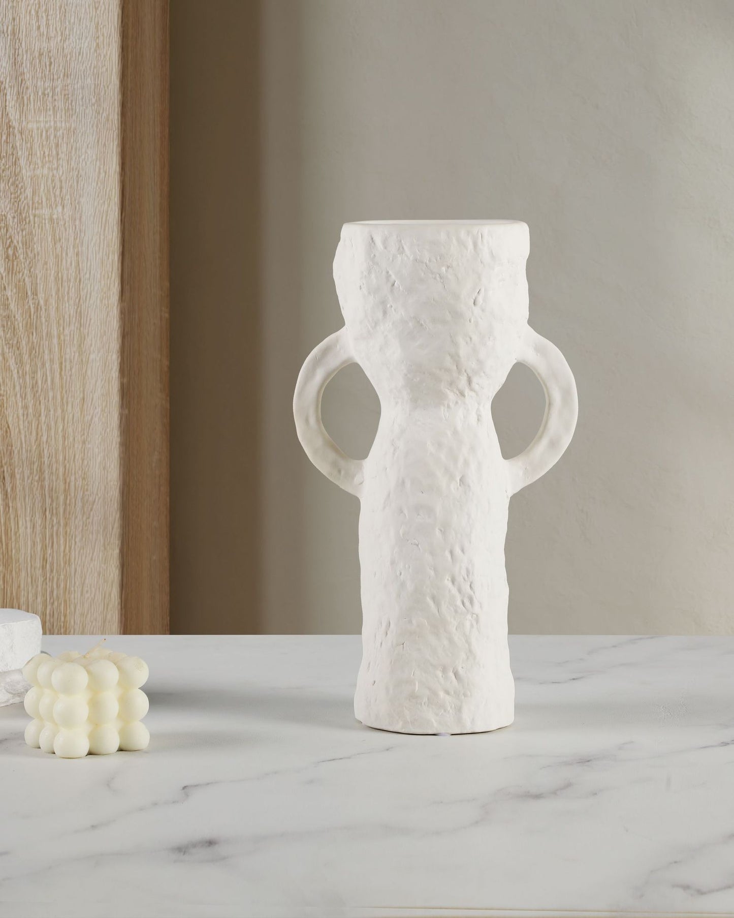 White textured vase on a marble surface with a neutral background
