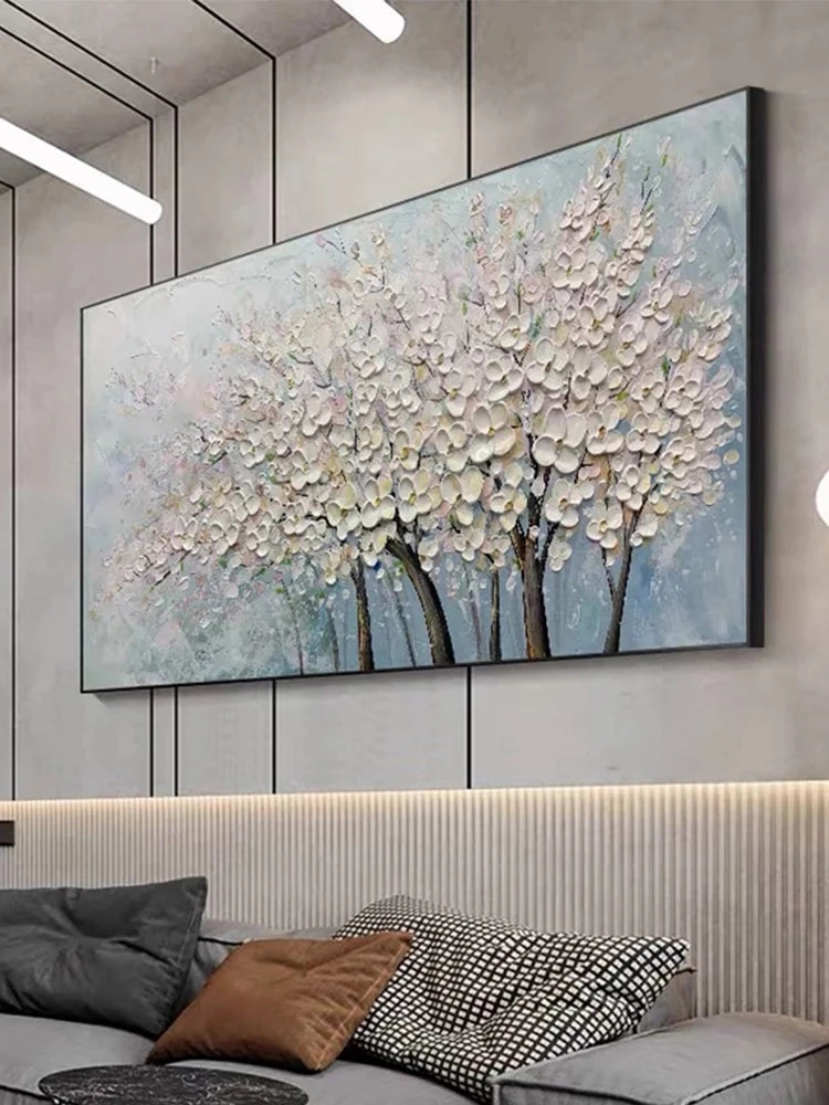 Abstract painting of trees with white flowers on a wall above a sofa.