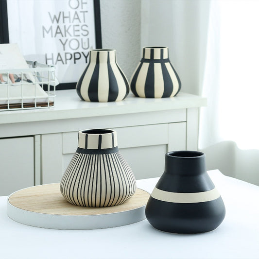 Black and white striped vases on a shelf and table in a room.