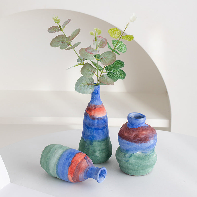 Set of three colorful vases with a plant on a white background