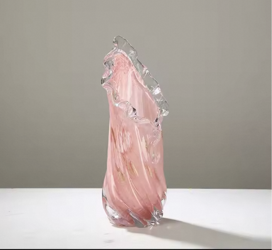 Pink glass sculpture on a white surface with a gray background