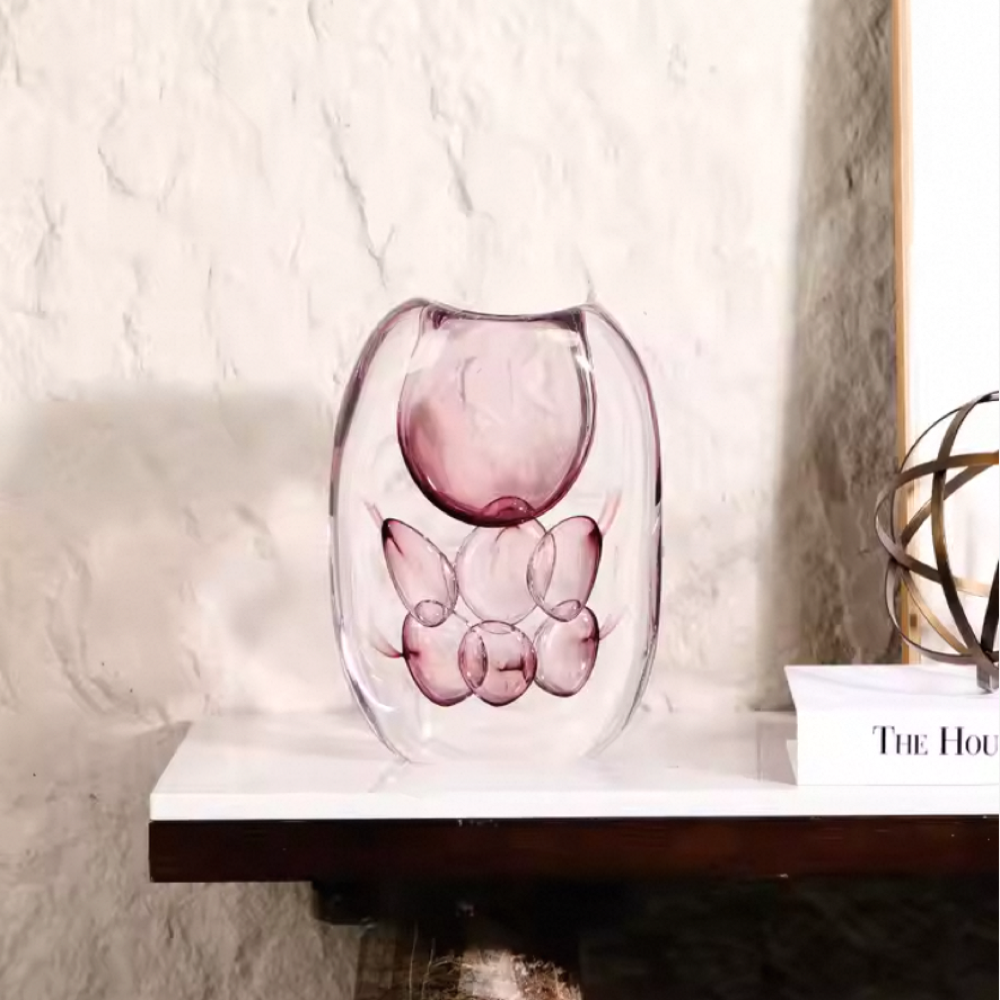 Pink glass vase on a white surface with a blurred background