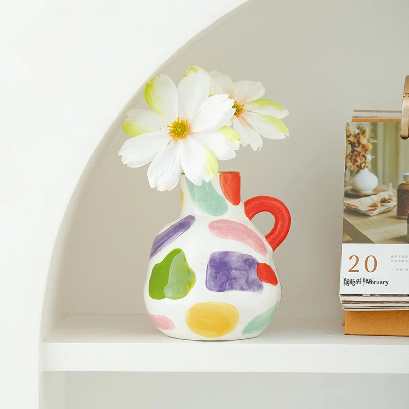 Colorful vase with a white flower on a shelf