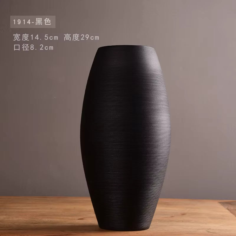 Black textured vase on a wooden surface with a gray background