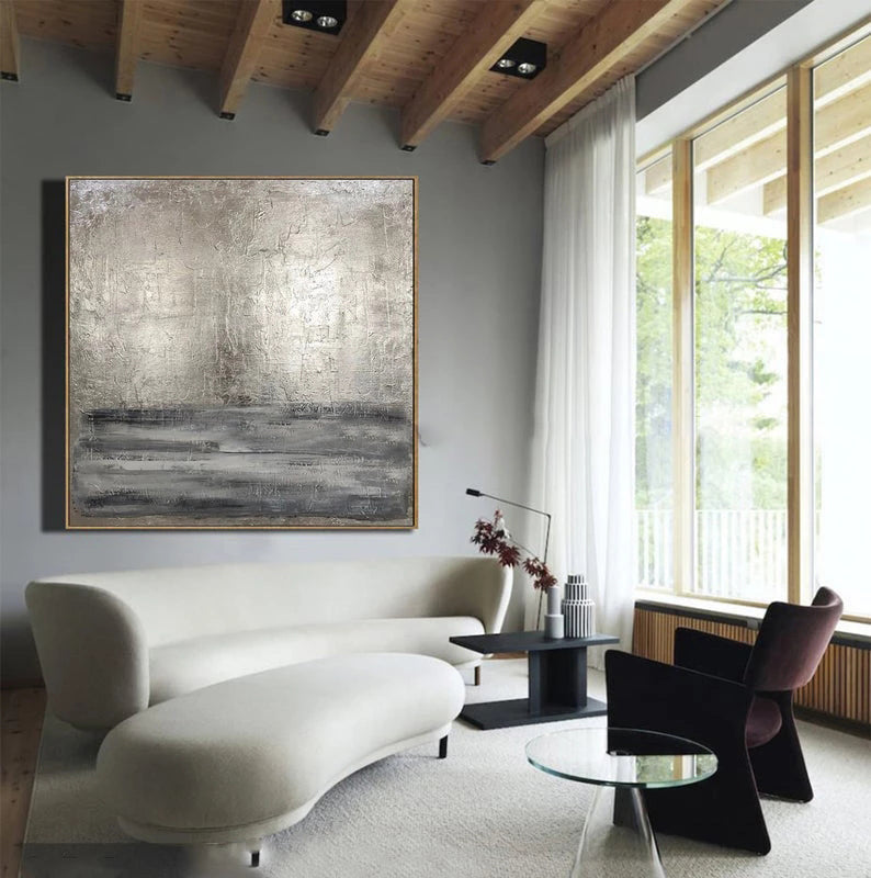 Modern living room with a white sofa, abstract painting, and large windows.