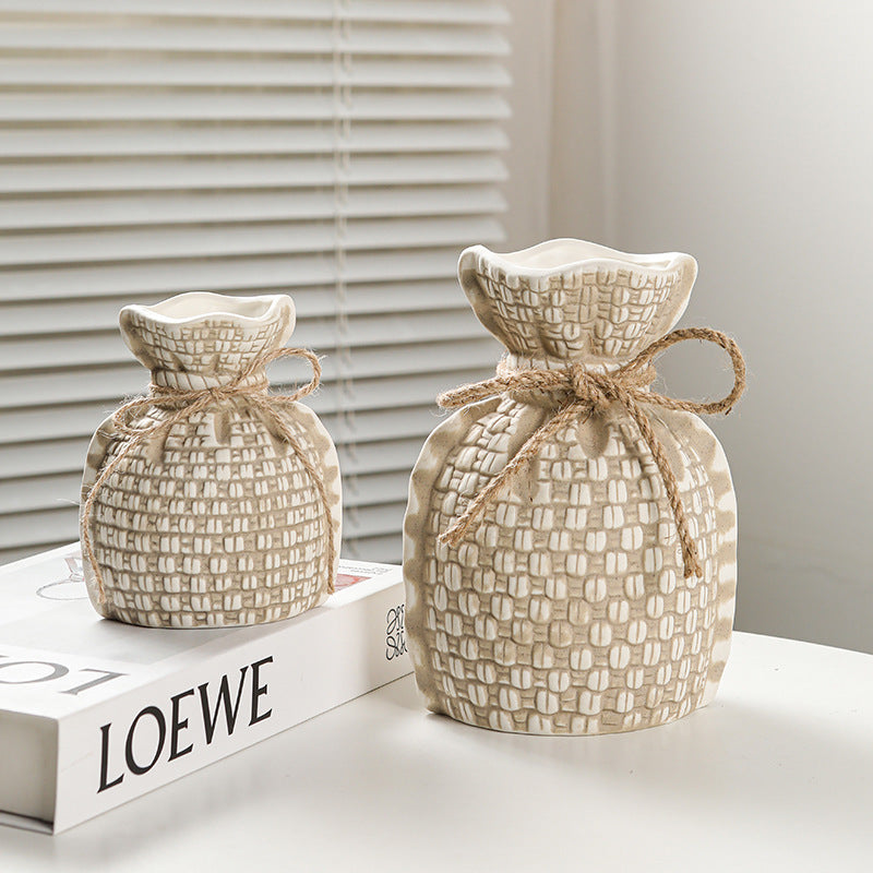 Two woven fabric bags tied with jute rope on a LOEWE box with a neutral background.