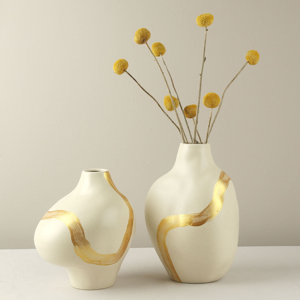 Two ceramic vases with gold accents on a neutral background
