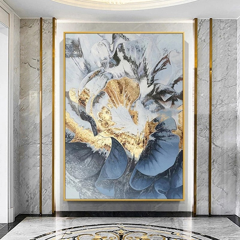 Abstract art piece with gold and blue tones in a gold frame on a marble wall.