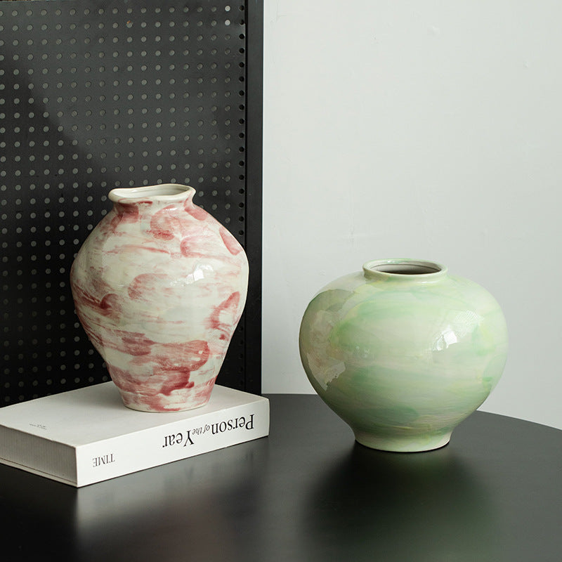 Two ceramic vases on a dark surface with a black and white patterned wall in the background.