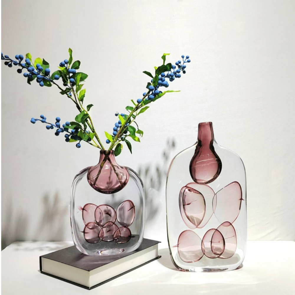 Two glass vases with pink interior and floral design on a white surface.