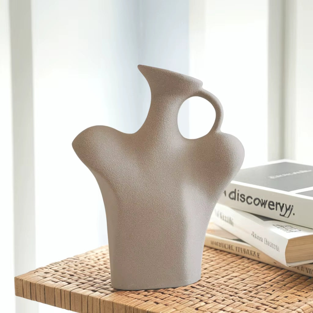 Beige ceramic vase on a wooden surface with books in the background