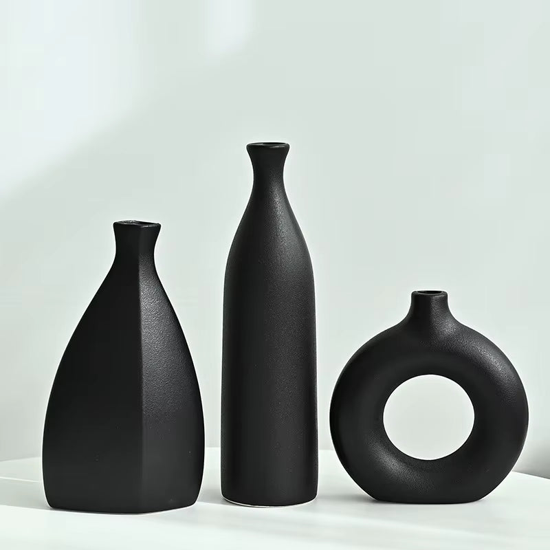 Three black vases of different shapes on a light gray background