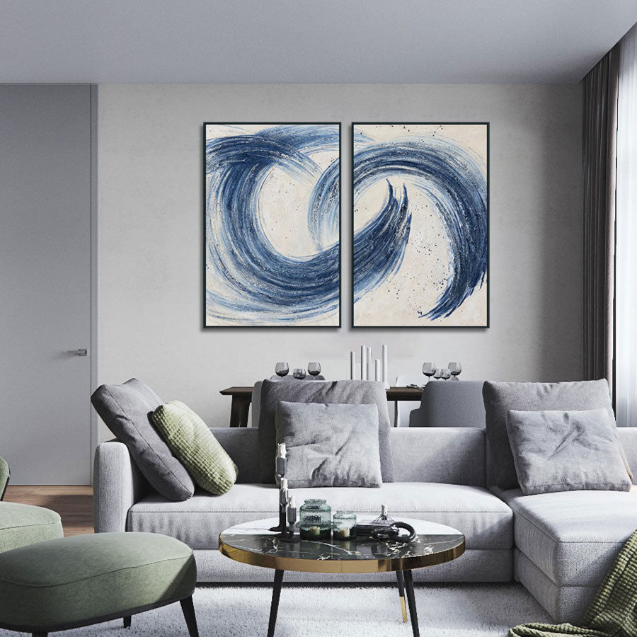 Modern living room with a gray sectional sofa, abstract blue artwork, and a round coffee table.