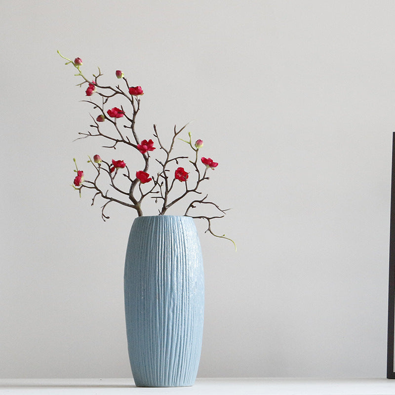 Blue textured vase with red flowers on a plain background