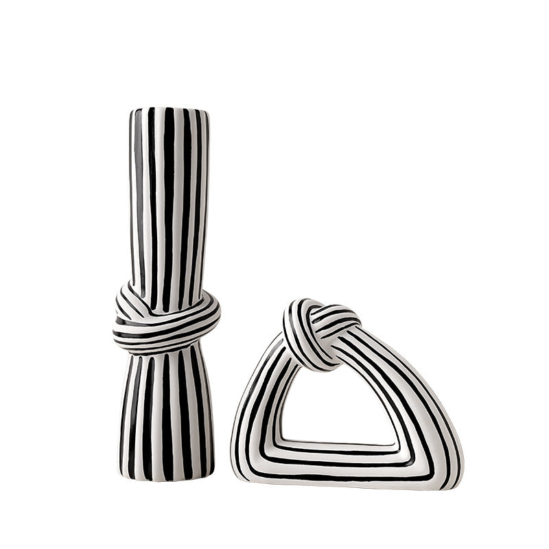 Black and white striped ceramic vase and triangle-shaped ornament on a white background