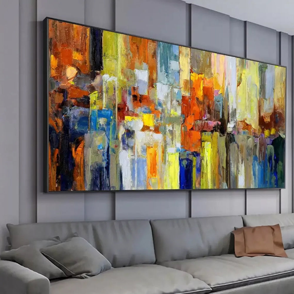 Abstract art painting on a wall above a gray sofa with cushions.