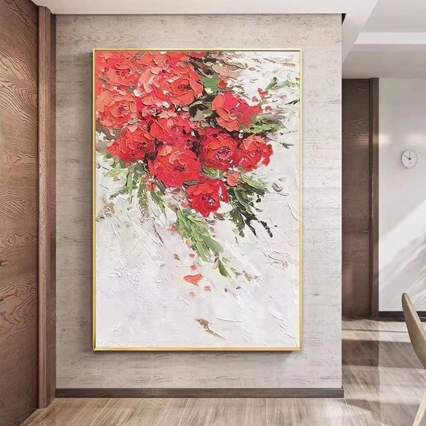 Floral painting with red flowers in a gold frame on a wall.