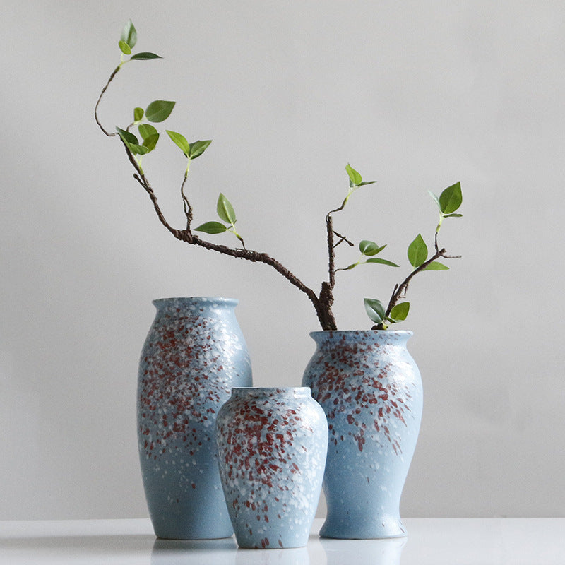 Three blue ceramic vases with speckled pattern on a white surface and light gray background.
