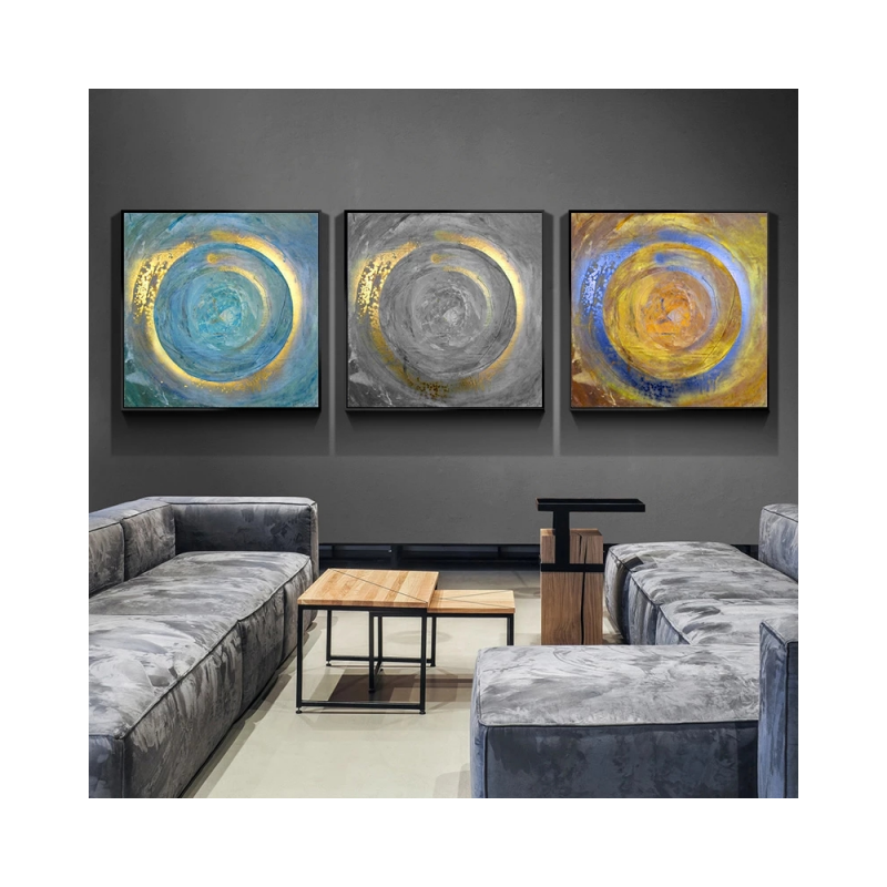 Three abstract wall art pieces on a gray wall above a modern living room setup.