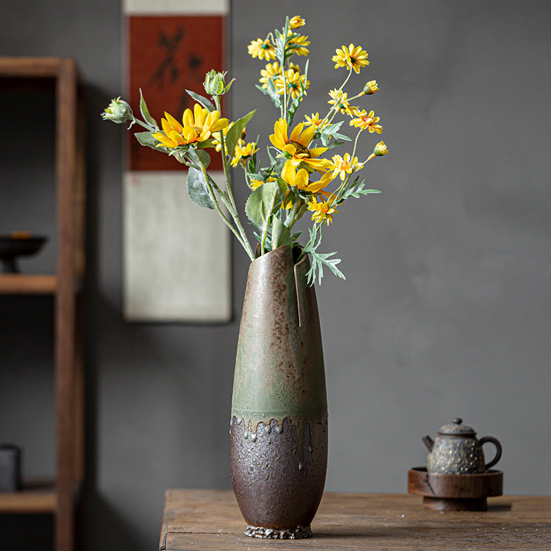Decorative vase with yellow flowers on a wooden table against a dark background
