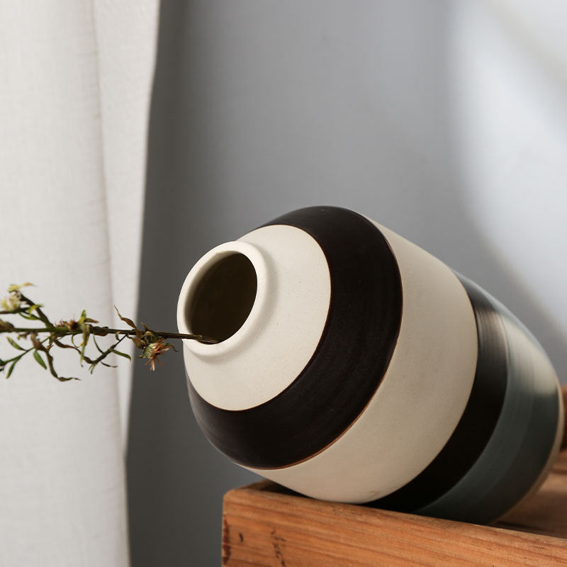 Black and white striped vase on a wooden surface with a neutral background