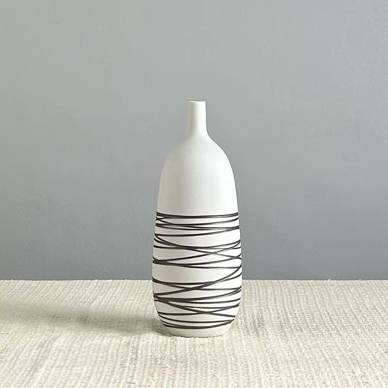 White vase with black wavy patterns on a textured surface and gray background