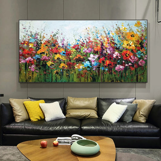 Colorful floral painting above a black leather sofa with decorative pillows in a living room.
