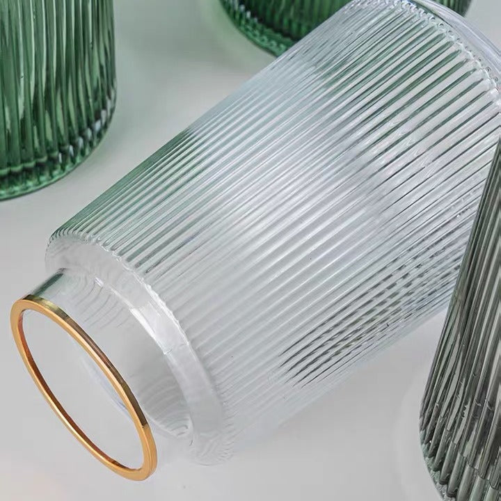 Clear ribbed glass vase with gold base on a light background