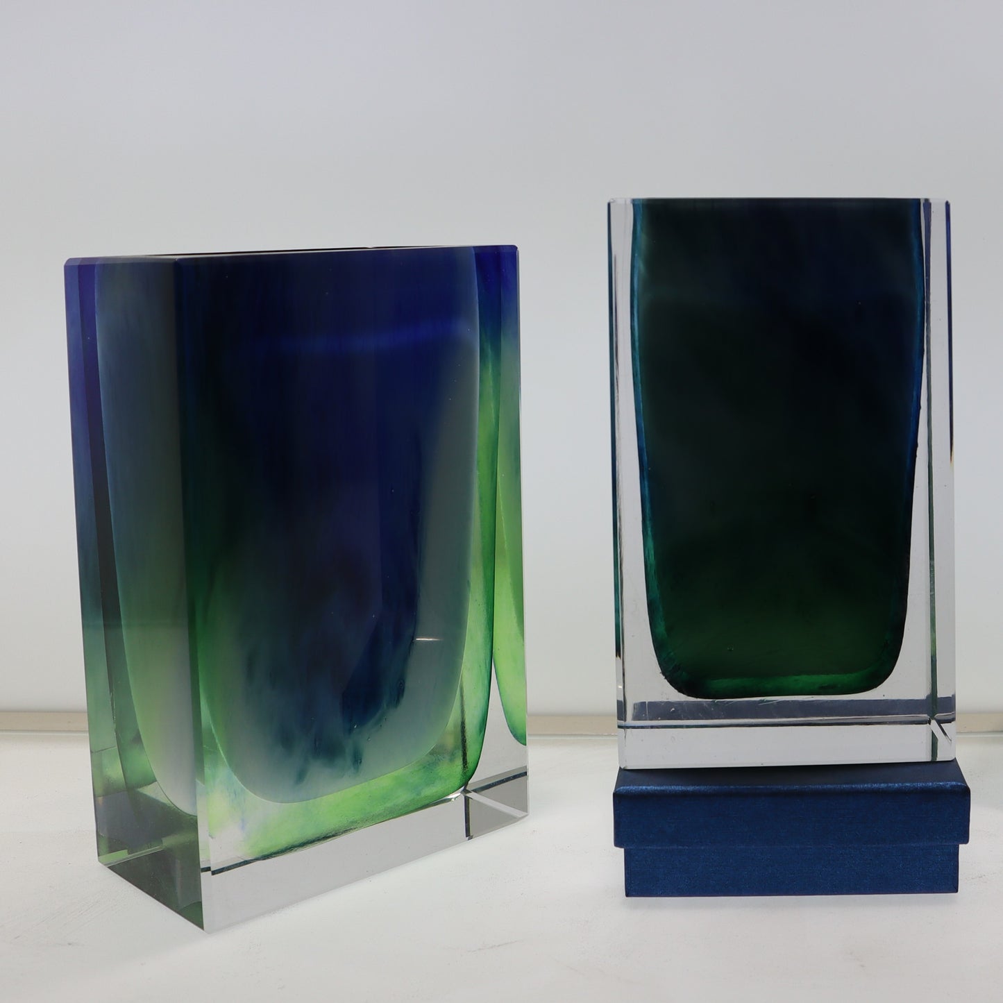 Two glass vases with blue and green gradient on a white background