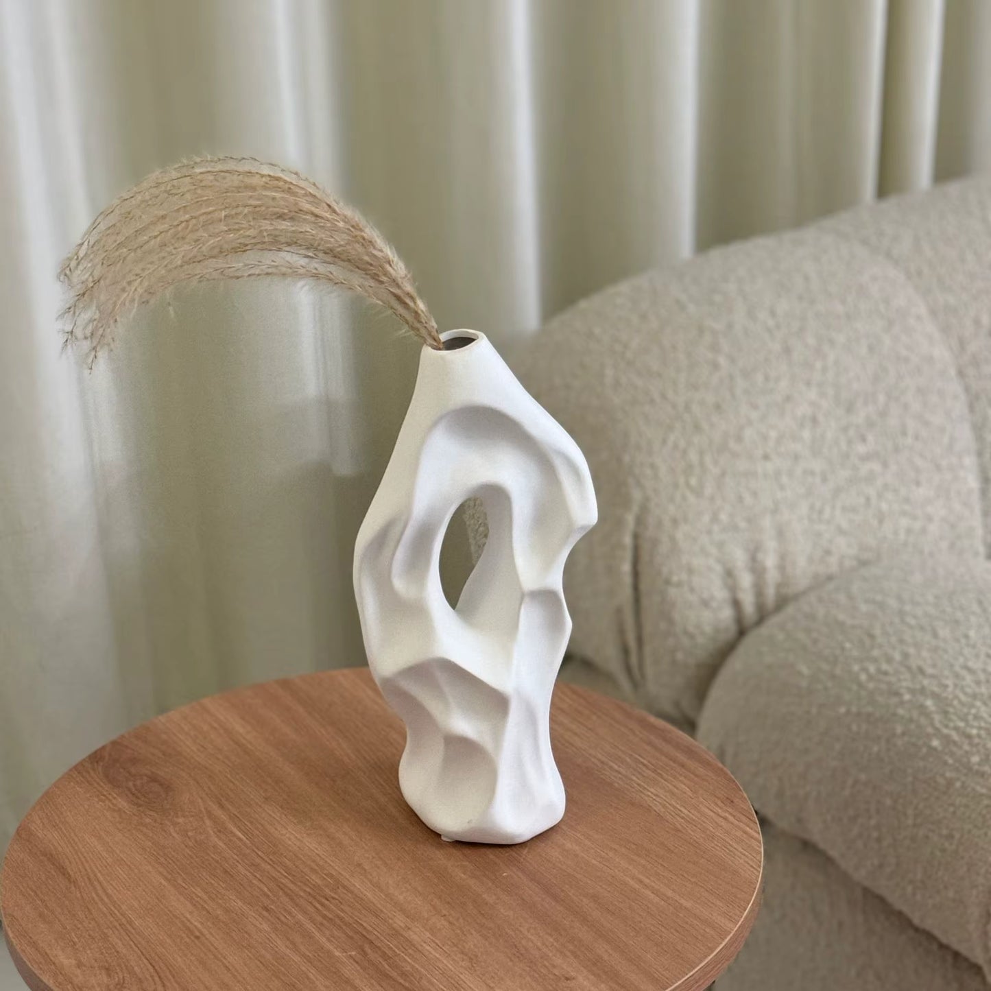 White abstract vase on a wooden surface with a neutral background