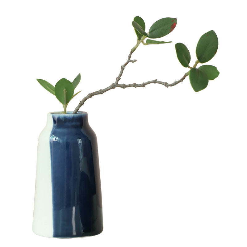 Blue and white vase with a branch and leaves on a white background