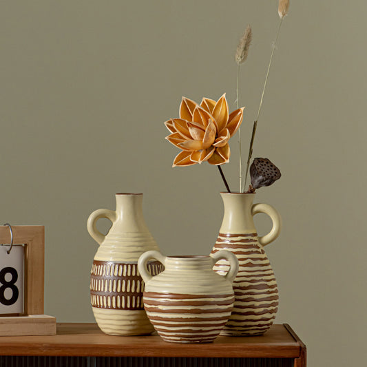 Three ceramic vases with decorative patterns on a wooden surface against a plain wall.