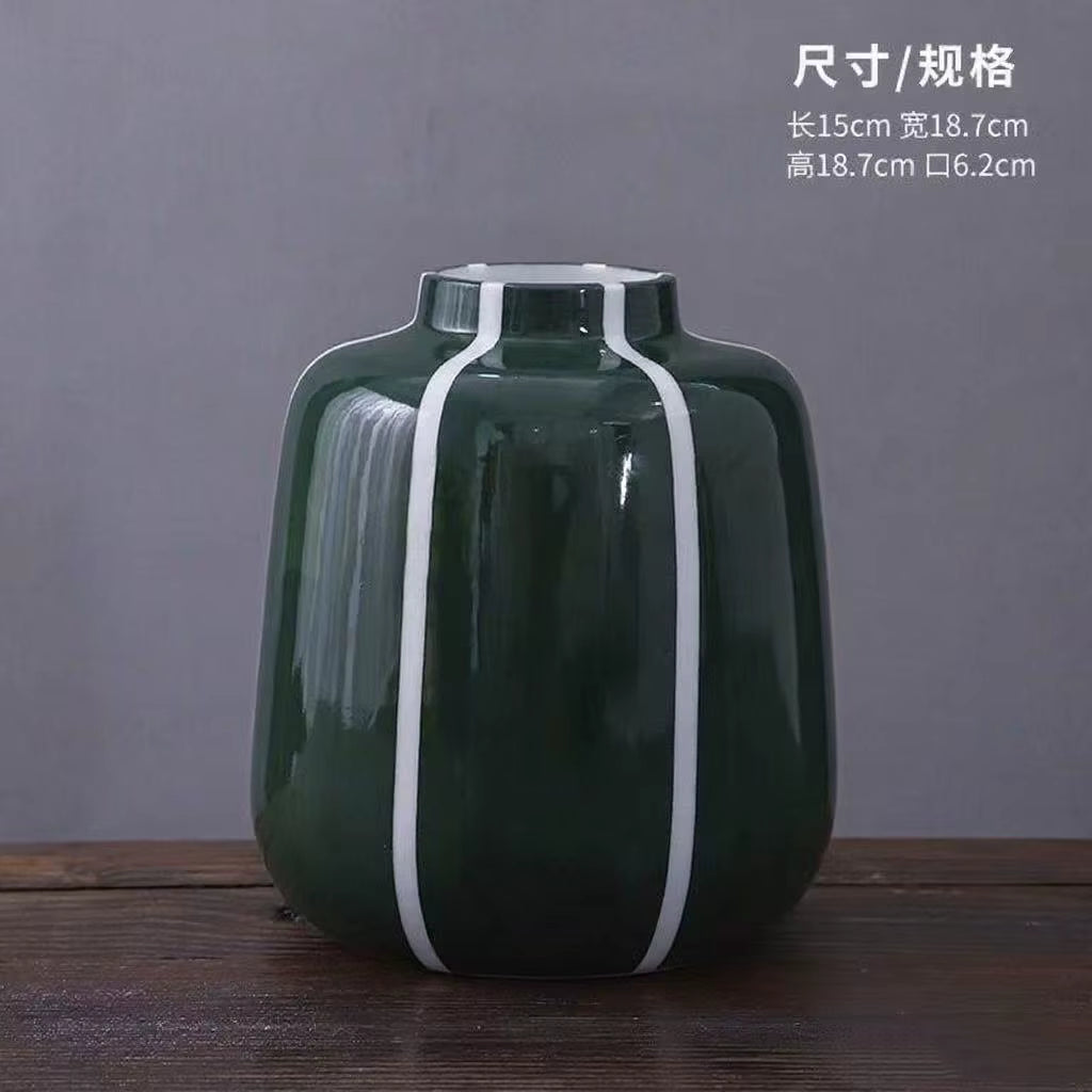 Green vase with white stripes on a wooden surface and gray background